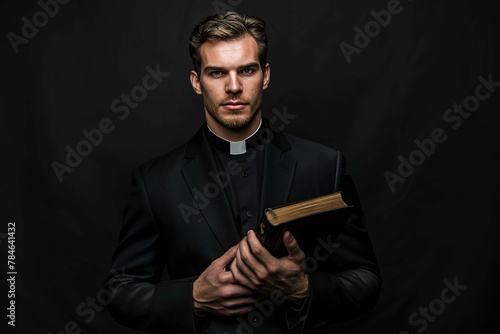 Catholic priest holding bible isolated on black background photo