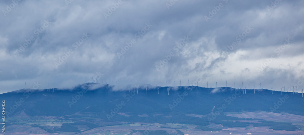 Obraz premium Clouds partially hide the wind turbines