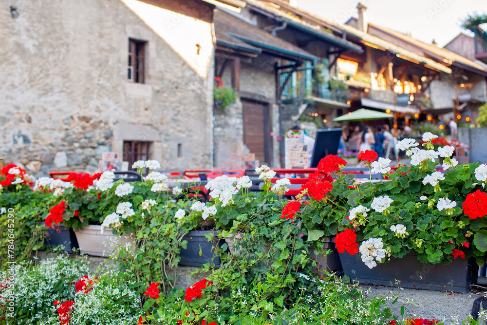 Naklejka premium Cafe in historic Yvoire, traditional stone building adorned with lush greenery and rustic wooden shutters, charm of small-town France