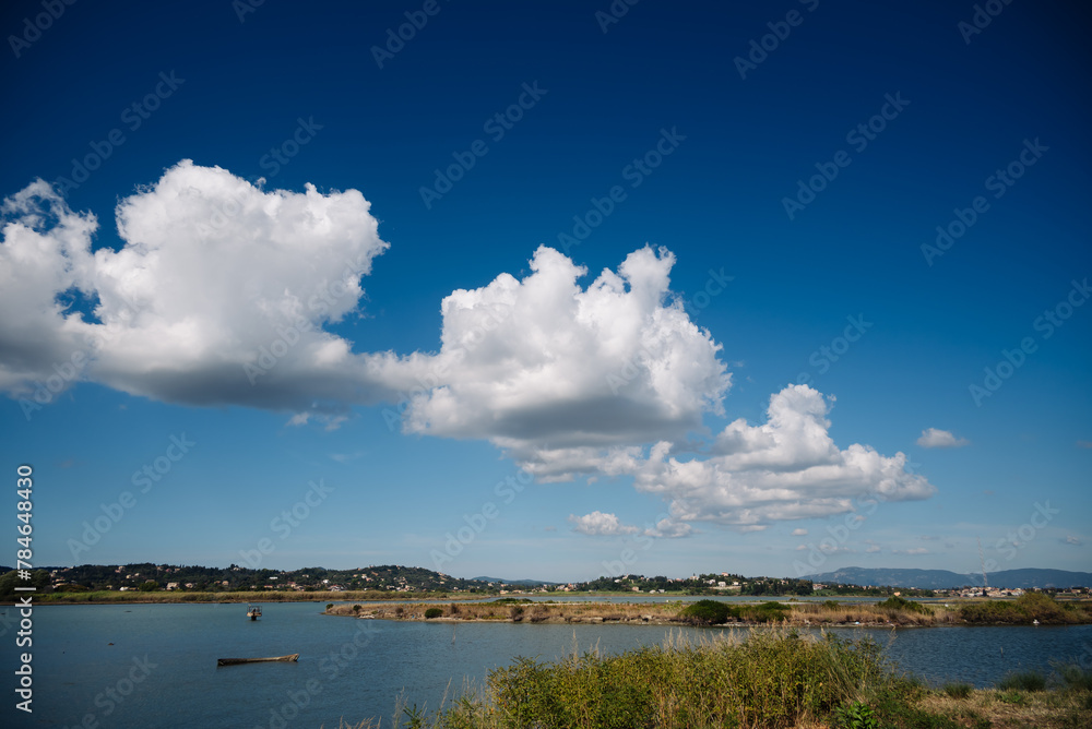 Lake reflecting a blue sky with white cumulus clouds in a natural landscape