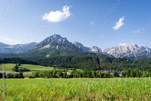 Österreiche Alpen in Tirol - das Hochgebirge des Wilden Kaisers mit grünen Wiesen und Feldern im Vordergrund.