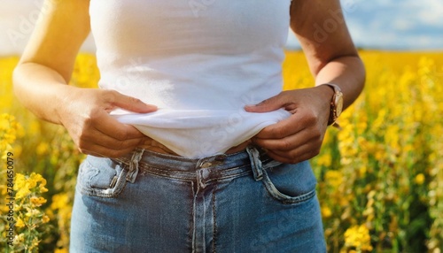 Woman touching belly fat on goldenrod background, closeup. Overweight problem