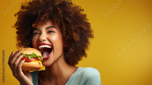 Joyful Woman Enjoying Delicious Burger on Yellow Background