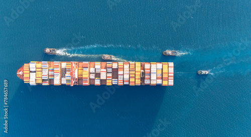 Top view Container ship full capacity approaching the port by a tugboat occupying the port International Container ship loading, unloading at sea port, Freight Transportation, Shipping,   Logistics,