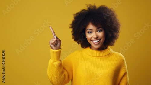 Cheerful African American Woman Pointing Upwards on Yellow Background
