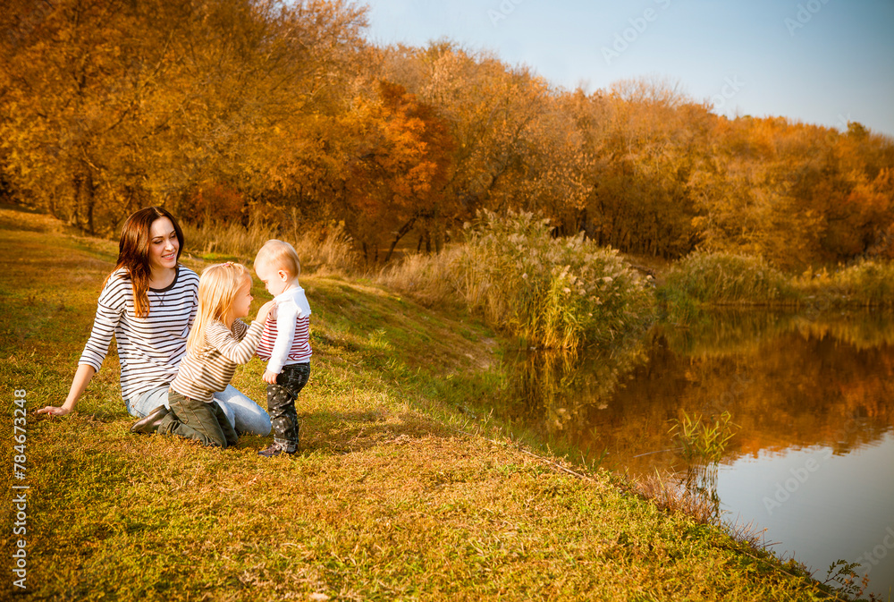 Portrait of smiling mother and daughters on autumn lake