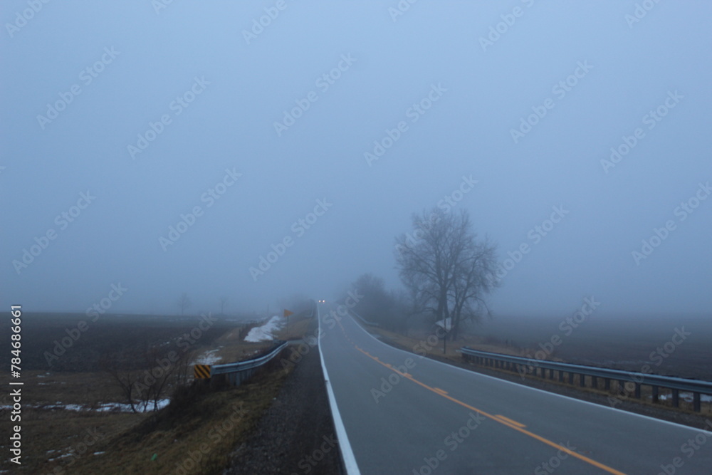 A car travels down a foggy road 