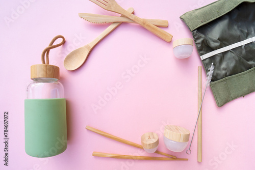 Zero waste concept, reusable eco-friendly straw and bottle for water over pink background, frame with copy space