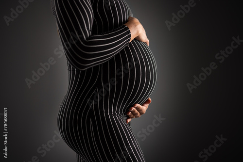 Elegant Pregnant Woman Embracing Her Belly in Striped Dress