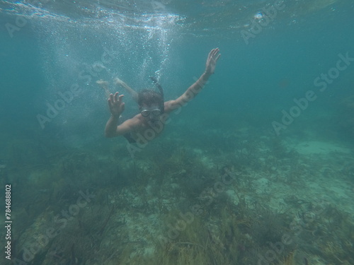 A man snorkels and swims underwater on a coral reef in the ocean