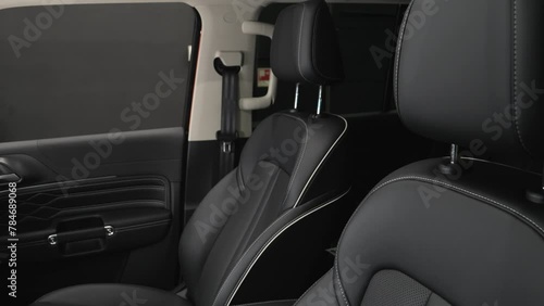 The camera slowly moves around the black interior of a premium car. The front seats of the car. Filming in the studio.