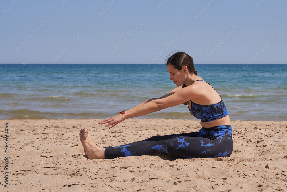Healthy woman in sportswear stretching the legs on the beach Healthy woman in sportswear stretching the legs on the beach