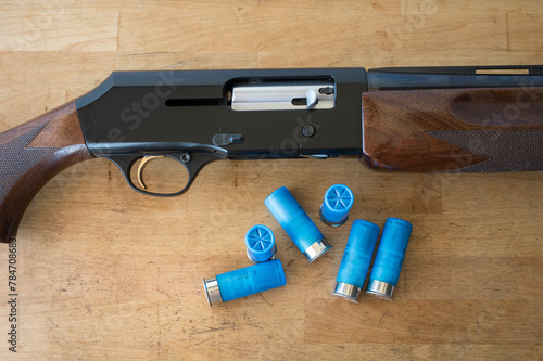 Detail of a 12 gauge semi-automatic shotgun and some shotshells on a wooden table