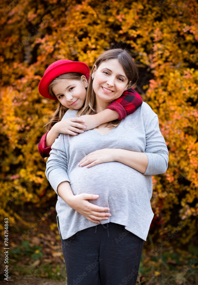 Happy young pregnant mother with daughter in autumn park Happy young pregnant mother with daughter in autumn park