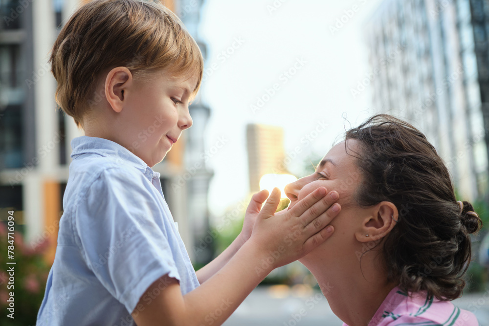 Adorable mother and son smiling happy having fun at city background. Motherhood concept, hugging. Boy 8 years old with mother in bright clothes enjoying summer day. High quality photo Adorable mother and son smiling happy having fun at city background. Motherhood concept, hugging. Boy 8 years old with mother in bright clothes enjoying summer day. High quality photo