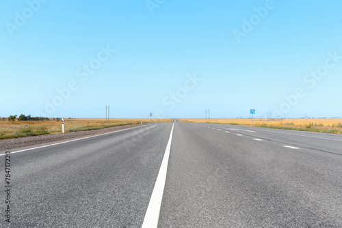 An asphalt road with markings stretches into the distance on a bright summer day. Beautiful road in the steppe. © Lexis_Jan