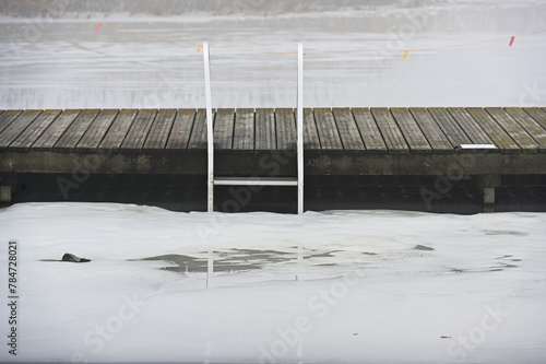 wooden pier and ladder on the lake in winter