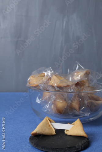 Fortune cookies in a jar bowl on a blue copy space background. Prediction text in cookies. Holiday traditions. New Year's Eve Entertainment