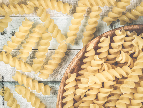 Raw italian fusilli spiral pasta on a wooden plate. Close up detail food photography.