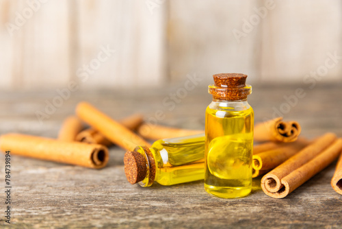 Cinnamon aromatic essential oil and cinnamon sticks on a wooden background. Aromatherapy. Organic cosmetic oil. Spa concept. Place for text. Copy space.