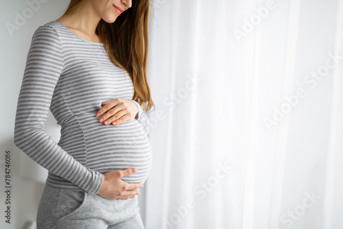 Pregnant woman holding belly in a cozy room