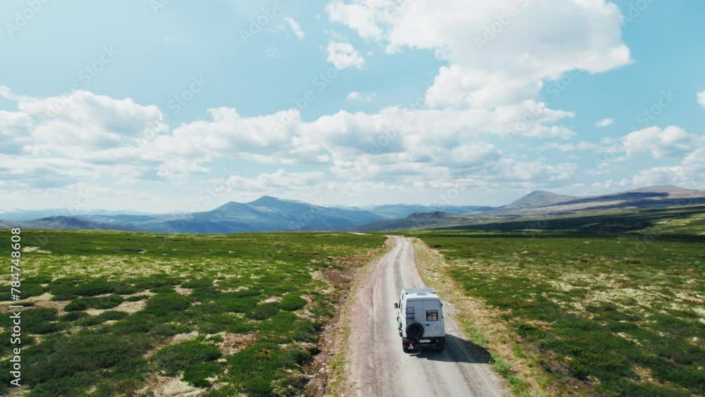 Drone follows 4x4 camper van drive on a gravel mountain road on sunny ...