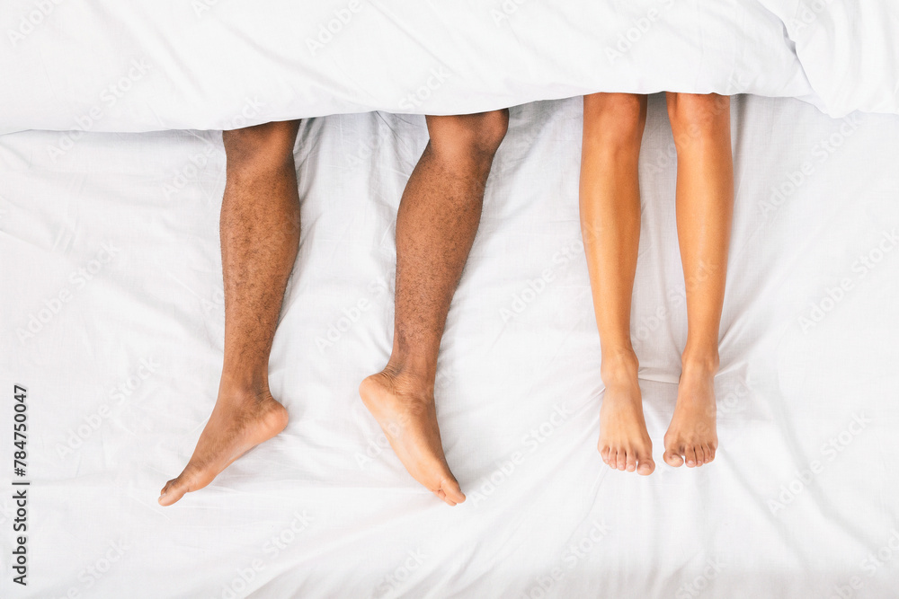 Male and female legs under duvet lying on bed Male and female legs under duvet lying on bed