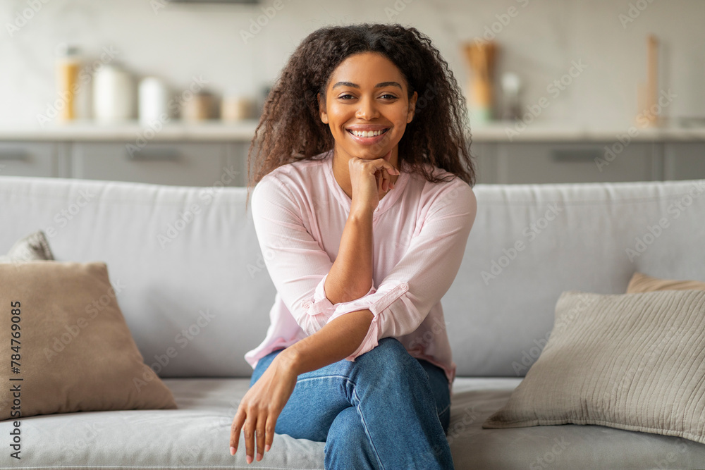 Smiling black lady seated on a sofa at home Smiling black lady seated on a sofa at home
