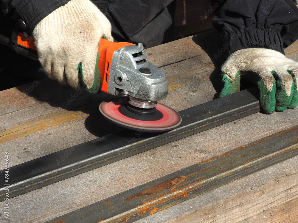 A worker processes metal with an angle grinder on a construction site.
The concept of locksmith work, processing of metal products.
