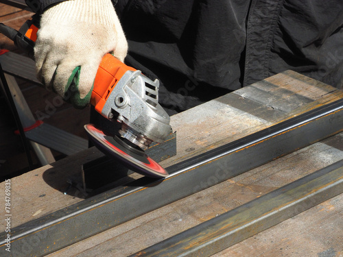 Obraz na płótnie A worker processes metal with an angle grinder on a construction site.
The concept of locksmith work, processing of metal products.
w salonie