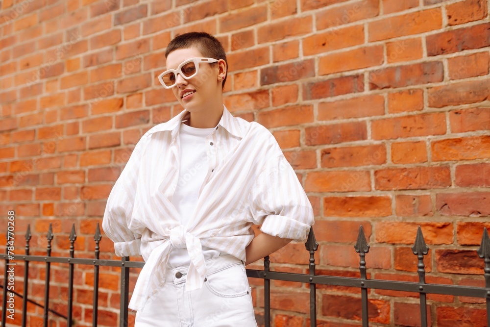 Portrait of a woman with a short haircut posing on the city streets. Female tourist enjoys the urban vibe of the streets of Europe. Portrait of a woman with a short haircut posing on the city streets. Female tourist enjoys the urban vibe of the streets of Europe.