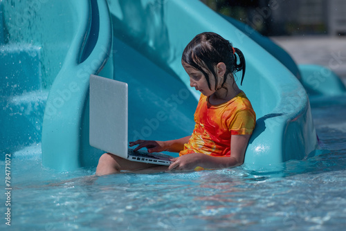 Learning and study everywhere and always. Portrait of young girl learning with laptop computer in the swimming pool water.