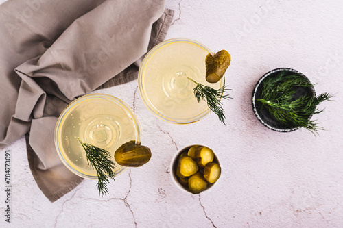 Trendy martini cocktails with pickles and dill in glasses on the table top view