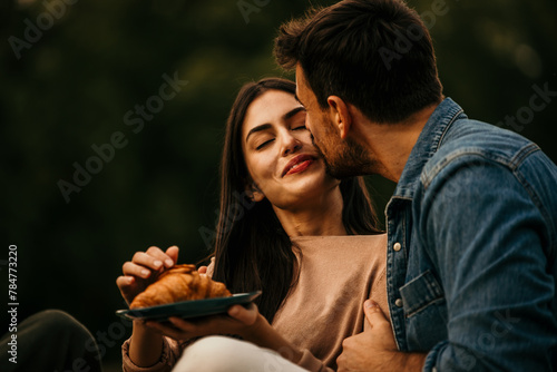Affectionate couple laughing and enjoying snacks during a picnic outing © La Famiglia