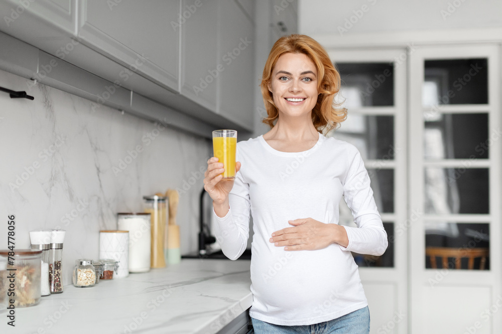 Smiling pregnant woman with orange juice in kitchen Smiling pregnant woman with orange juice in kitchen