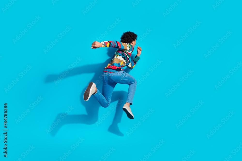 Full length photo of handsome young guy running back hurry black friday dressed stylish print garment isolated on blue color background Full length photo of handsome young guy running back hurry black friday dressed stylish print garment isolated on blue color background