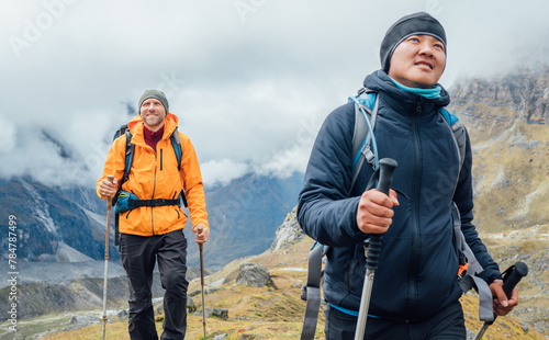 Caucasian and Sherpa men backpackers with trekking poles together hiking and enjoying Mera peak climbing acclimatization walk Makalu Barun Park route. Men enjoying Togetherness and beautiful valley. © Soloviova Liudmyla