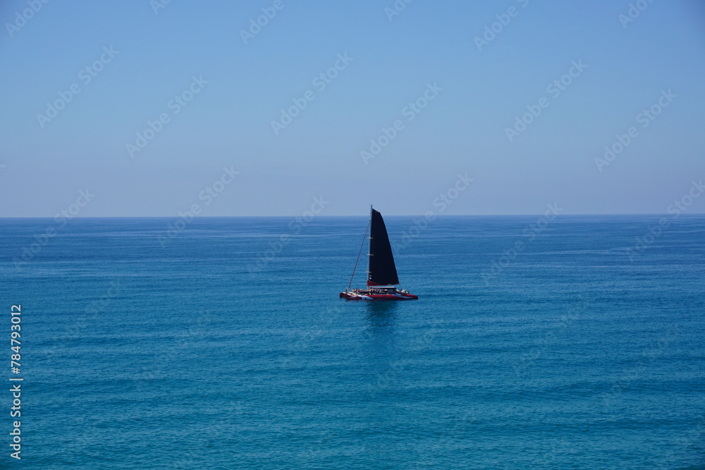  A Sailboat Sailing in the Middle of the Ocean. The boat is moving steadily through the water, driven by the wind.