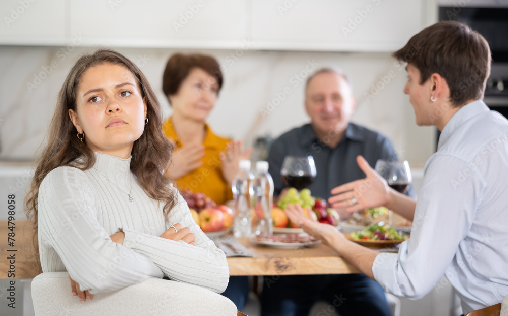 Upset young woman at family holiday table with parents at home. Unpleasant discussion