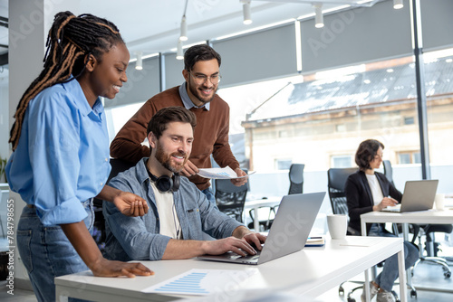 Team of diverse business professionals using laptop while working together