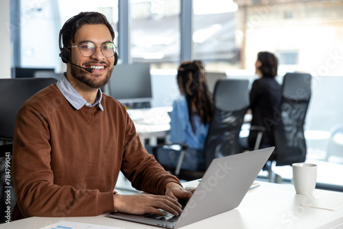 Smiling businessman call center agent wearing headset at workplace © zinkevych