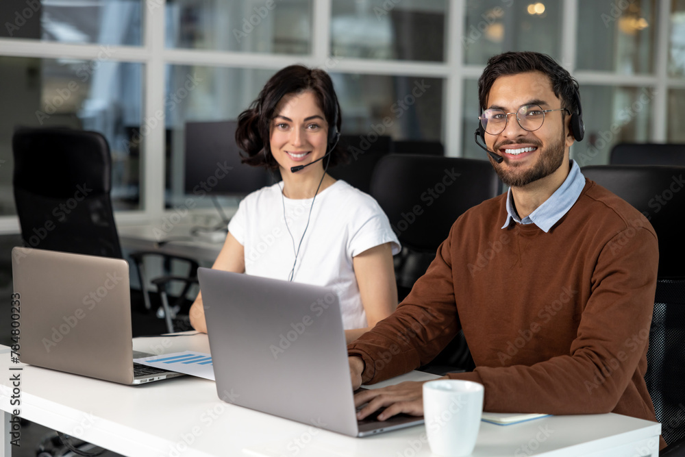 © zinkevych - Office employees in headset using laptop for work in coworking space