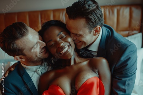 The concept of a threesome. A woman and two men in love. An African woman in a red dress and two men in suits in the same bed. Polygamy or bigamy. photo