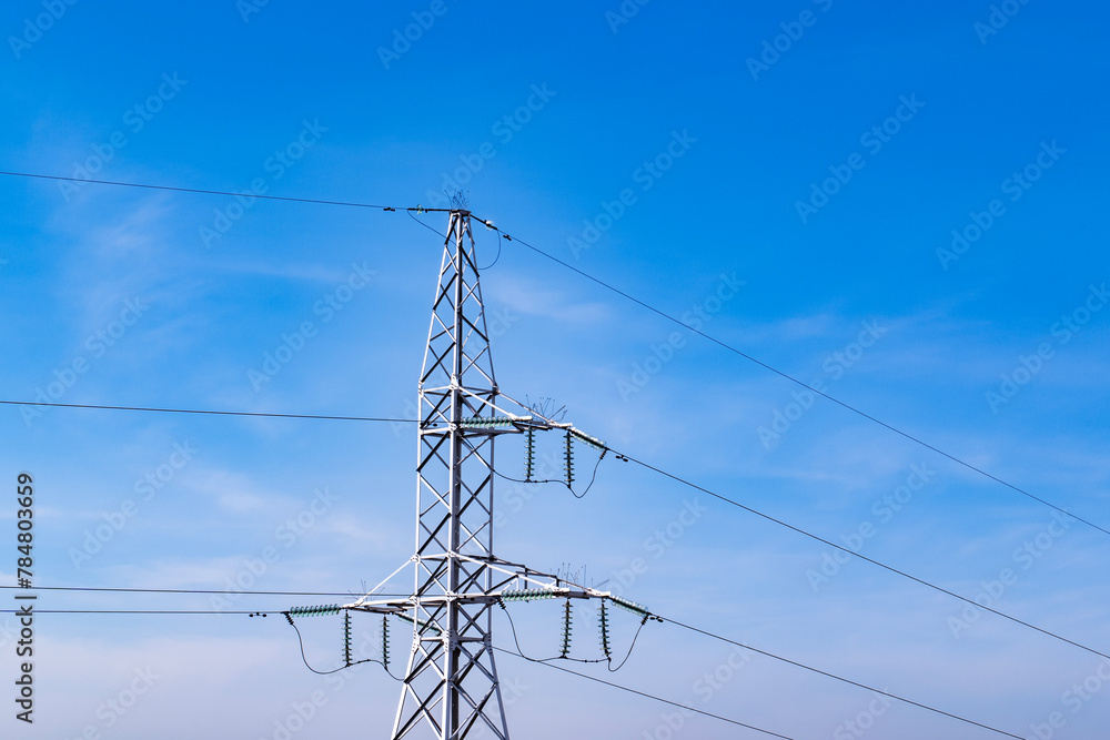 Energy infrastructure. High voltage electric transmission pylon, or tower, against blue sky. Close-up. Copy space.