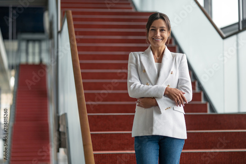 Pretty business woman in white jacket going down the stairs