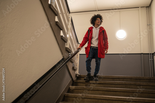 Guy in red jacket going downstairs and looking aside