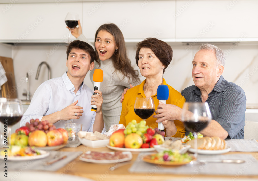 Friendly family with adult children singing karaoke together at home