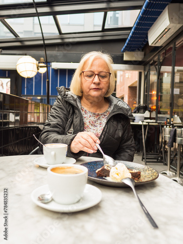 senior blonde eats sweet brownie dessert with concern
