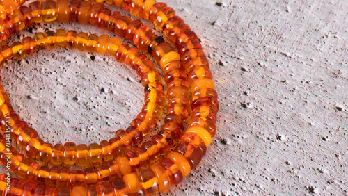 Orange Baltic amber necklace on concrete. Transparent   old amber jewelry close up. Natural sunstone. 