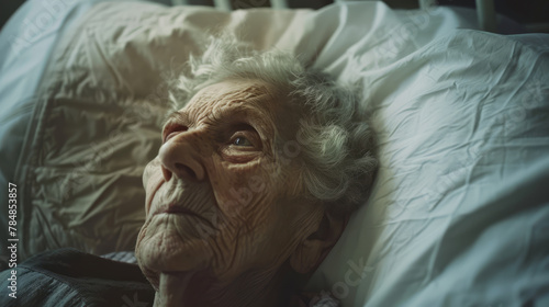 Portrait photo of sad old female patient in hospital's bed. 